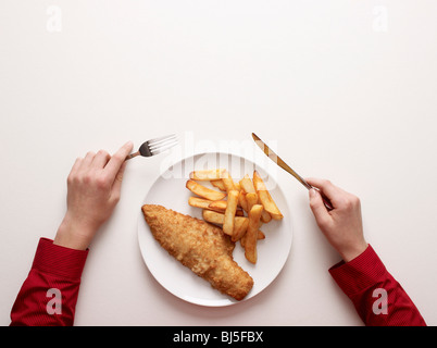 Mains par une assiette de poisson et frites Banque D'Images