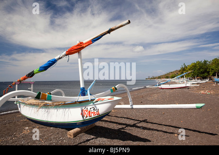 L'INDONÉSIE, Bali, Lombok, peintes de couleurs vives outrigger bateaux de pêche sur la plage de sable volcanique noir Banque D'Images