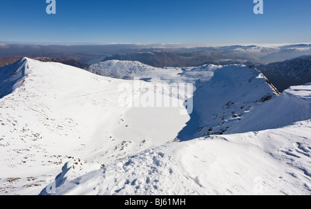 Vue d'hiver sur le Tarn rouge congelée de Helvellyn, Catstye came sur la gauche et marcher sur le bord droit, de Lake District. Banque D'Images