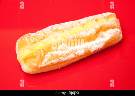 Crème pâtissière donut isolé sur un fond rouge studio. Banque D'Images