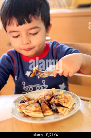 Boy eating pancakes aux myrtilles. Banque D'Images