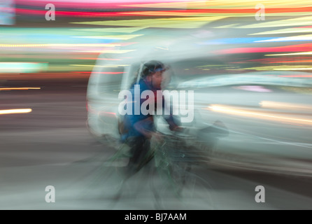 Un cycliste à travers les lumières de Times Square dans la nuit dans la ville de New York. Banque D'Images