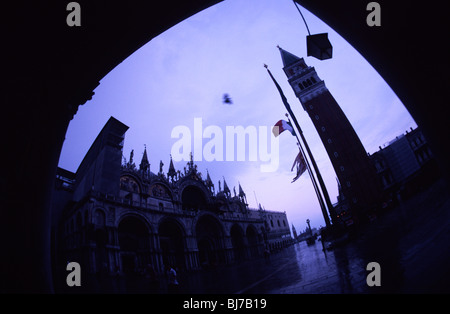 Venise, juillet 2008 -- un pigeon vole par sur la Place St Marc après une averse, drapeau italien sur le mât. Banque D'Images