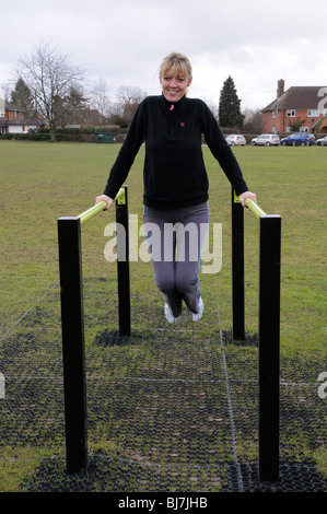 Femme à l'aide de barres parallèles de sport en plein air de l'équipement fournis pour utilisation publique dans un parc Berkshire England UK Banque D'Images