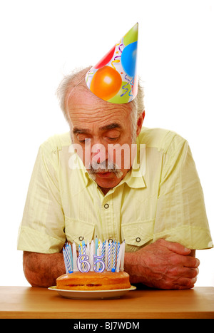 Man blowing out candles 65e anniversaire Banque D'Images