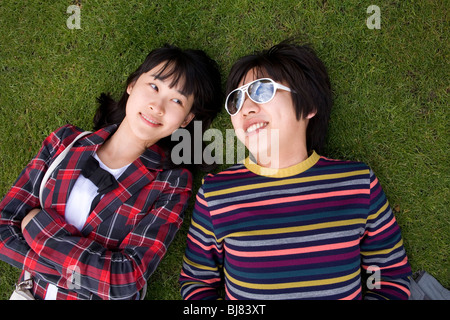 Young Asian couple couché dans l'herbe dans des vêtements colorés Banque D'Images