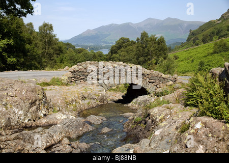 Ashness Pont sur Barrow Beck, avec de l'eau et la Derwent Derwent Fells en arrière-plan. Banque D'Images