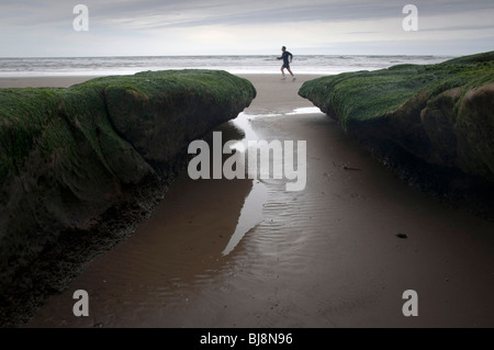 Un runner jogging le long d'une plage de la Californie dans le sable. Banque D'Images