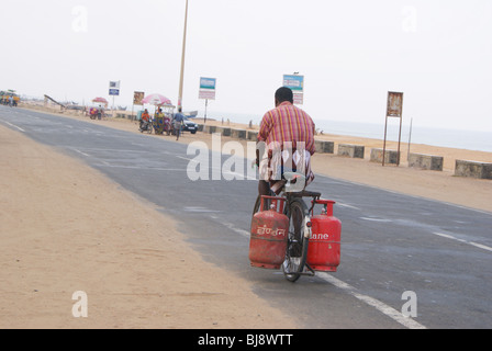 Un pauvre homme dangereusement transportant deux cylindres à gaz dans sa bicyclette sans mesures de sécurité.Randonnée homme de scène Kerala Inde Banque D'Images