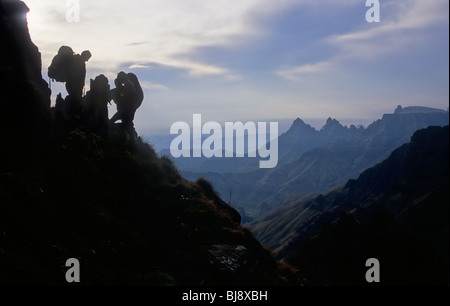 Les randonneurs qui se profile sur un versant de la Drakensberg avec Cathedral Peak dans la distance. Kwazulu Natal Afrique du Sud Banque D'Images