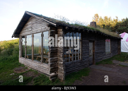 Chalet en bois avec toit engazonnées et de grandes fenêtres, tente à l'arrière-plan Banque D'Images