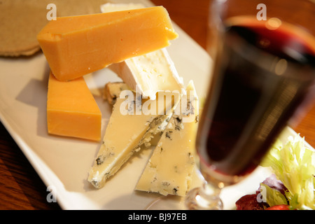 Close up de fromages en tranches sur le plateau avec un verre de porto en premier plan Banque D'Images