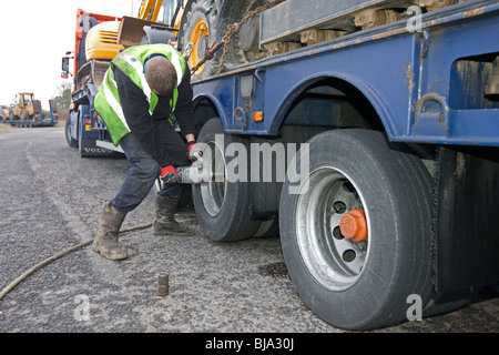 Un pneu d'ajusteur travaillant sur un camion en train de changer de roue sur la route Banque D'Images