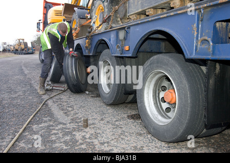 Un pneu d'ajusteur travaillant sur un camion en train de changer de roue sur la route Banque D'Images