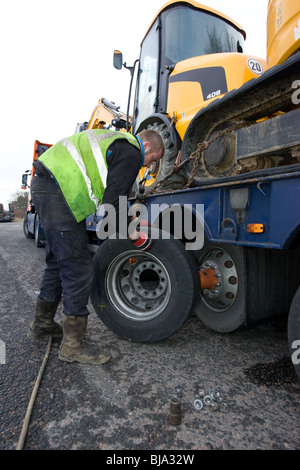 Un pneu d'ajusteur travaillant sur un camion en train de changer de roue sur la route Banque D'Images