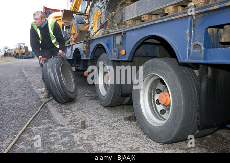 Un pneu d'ajusteur travaillant sur un camion en train de changer de roue sur la route Banque D'Images