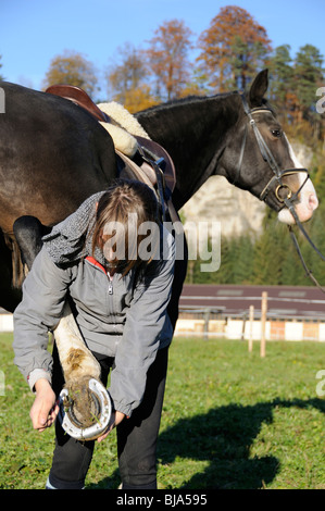 Le raclage de fille de sabot d'un cheval avec un sabot pick Banque D'Images