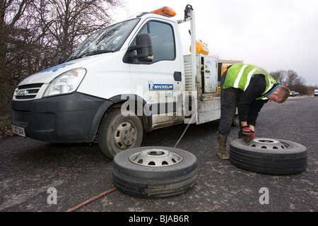 Un pneu d'ajusteur travaillant sur un camion en train de changer de roue sur la route Banque D'Images