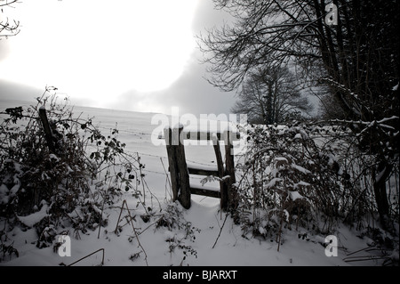 Bien faibles à travers les nuages sur paysage d'hiver Banque D'Images