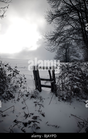 Bien faibles à travers les nuages sur paysage d'hiver Banque D'Images