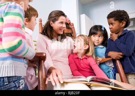 La lecture de l'enseignant livre multi-raciale groupe de jeunes enfants d'âge préscolaire Banque D'Images