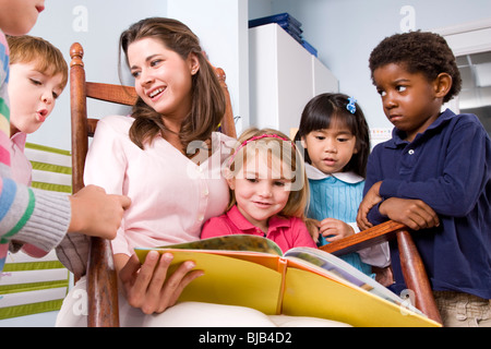 La lecture de l'enseignant livre multi-raciale groupe de jeunes enfants d'âge préscolaire Banque D'Images