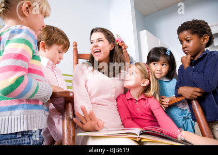 La lecture de l'enseignant livre multi-raciale groupe de jeunes enfants d'âge préscolaire Banque D'Images