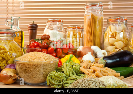 Un affichage d'aliments sains, y compris divers légumes, bols de pâtes, de riz, de graines, d'oignons, ail, huile d'olive et tomates Banque D'Images