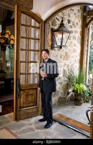 Asian man standing in hall par ouvrir la porte frontale de l'élégant home Banque D'Images