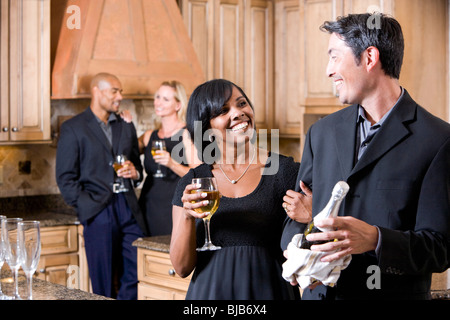 Homme avec bouteille de champagne dans la cuisine à discuter avec tes amis Banque D'Images
