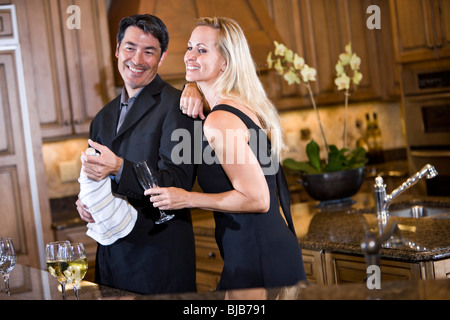 Mid-adult couple interracial ouverture bouteille de champagne dans la cuisine d'accueil Banque D'Images