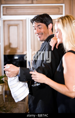 L'Interracial couple bouteille de champagne dans la cuisine Banque D'Images