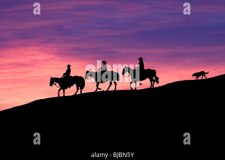 Silhouette de trois cowboys équitation suivie des au coucher du soleil Banque D'Images