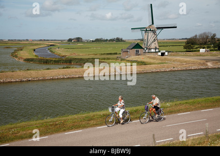 Les touristes à vélo passé, moulin à vent traditionnel de Moll - Oost, île de Texel, Hollande Banque D'Images