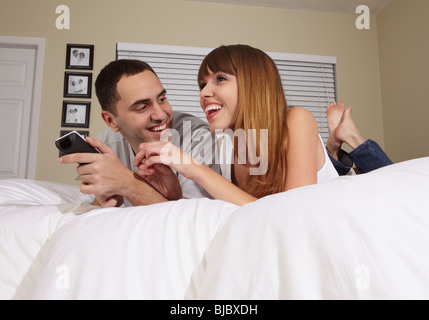 Mari et femme hispanique à regarder la télévision dans la chambre Banque D'Images