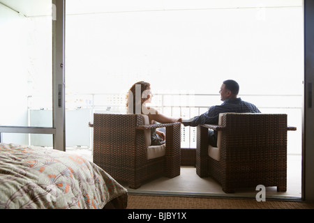 Couple assis dans des fauteuils et tenir la main sur balcon urbain Banque D'Images