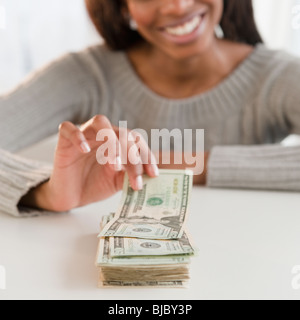 Mixed Race woman taking money de la pile Banque D'Images