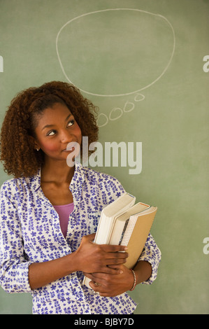 Mixed Race woman standing next to bulle pensée on blackboard Banque D'Images