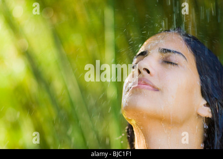 Jeune femme sous l'eau qui tombe, portrait Banque D'Images