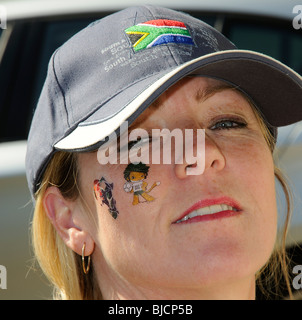 Portrait d'une femme portant un chapeau d'Afrique du Sud et le port de la Coupe du Monde 2010 tatouages sur son visage Banque D'Images