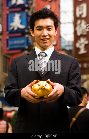 Homme debout sur une rue de la ville avec une tirelire. Banque D'Images