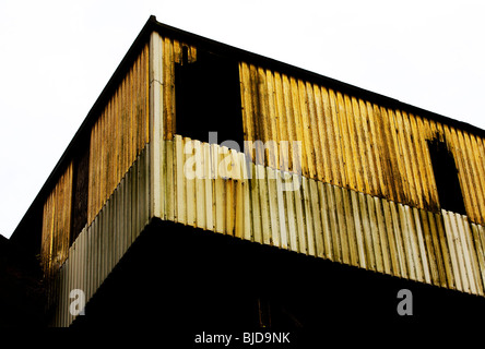 Faible point de vue d'un ancien bâtiment en tôle ondulée rouillée sur le bord d'une usine à l'abandon Banque D'Images