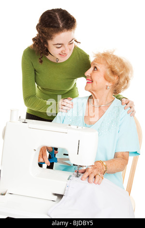 Teen girl regarder sa grand-mère coudre sur une machine à coudre. Isolées. Banque D'Images