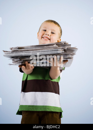 Enfant tenant une pile de journaux Banque D'Images