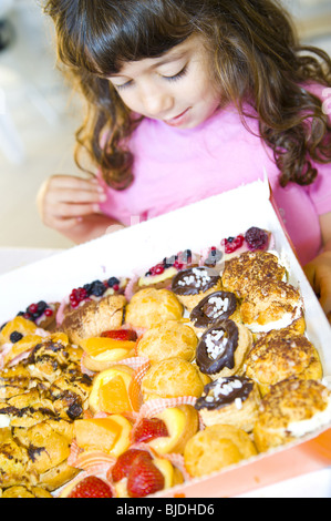 Petite fille tenter par un plateau de pâtisseries Banque D'Images