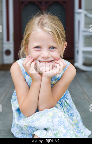 Fille assise sur le porche de devant Banque D'Images