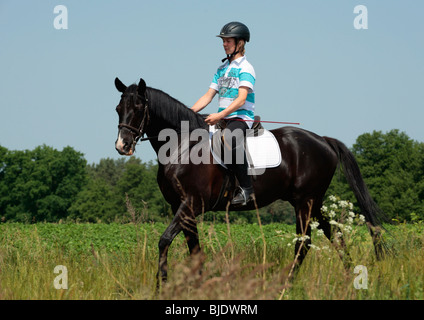 Teenage boy riding un étalon noir Banque D'Images