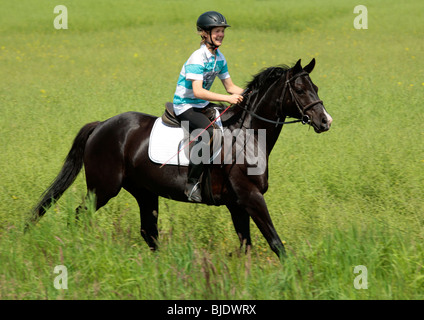 Teenage boy riding un étalon noir Banque D'Images