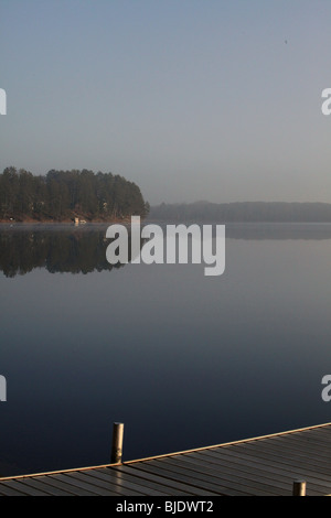 Un seul quai de brume matinale reflète une image en miroir dans le nord du lac WIFI crée une vue magique sur l'horizon lointain Banque D'Images