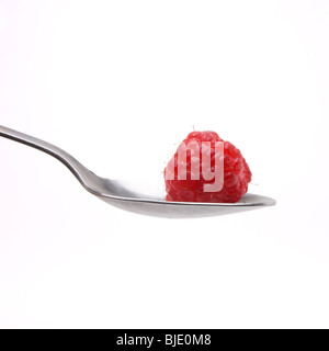 Assis dans un bol de framboises de Cuillère en acier inoxydable isolés contre fond blanc. Banque D'Images